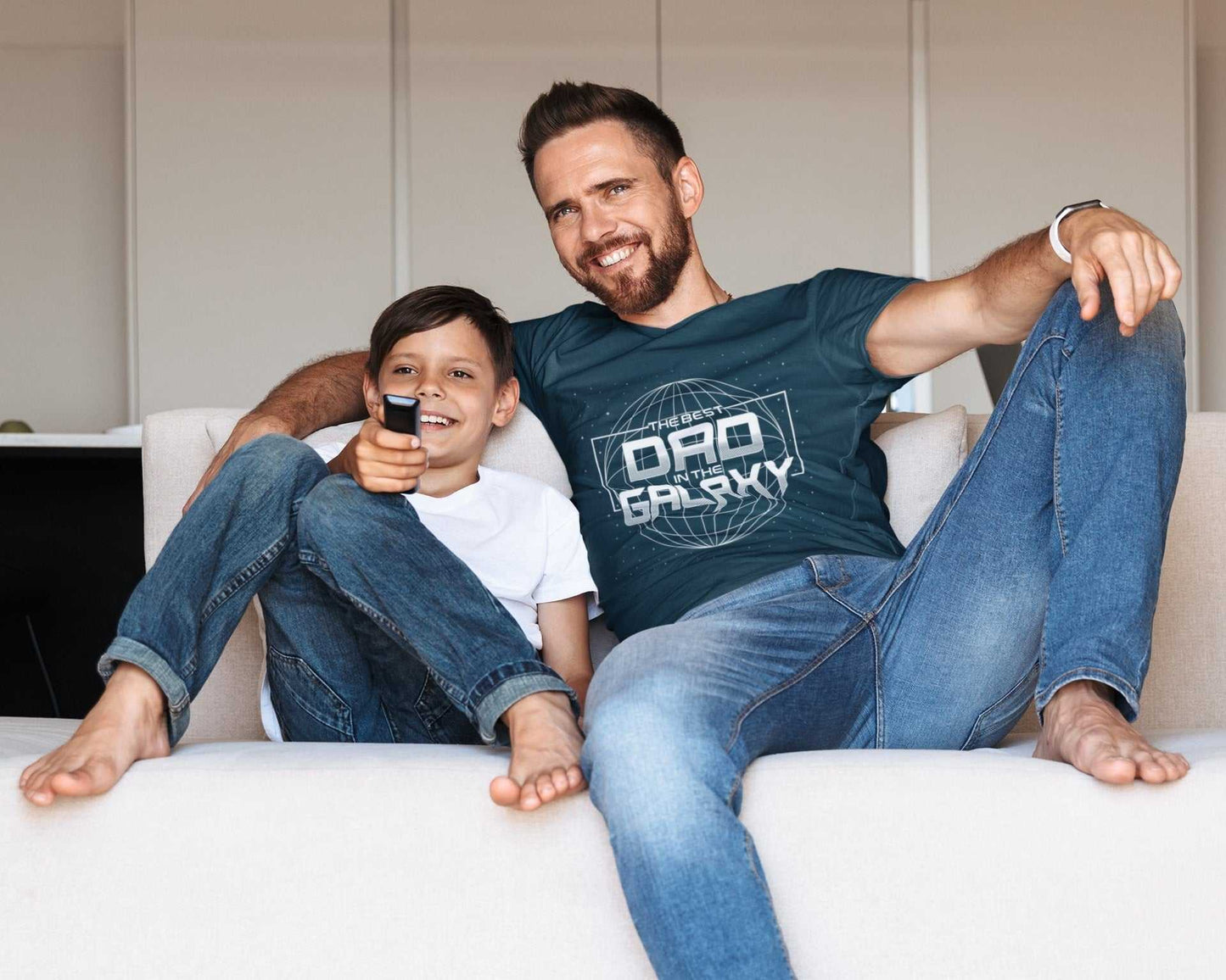 Father and son on couch, dad wearing "Best Dad in the Galaxy" t-shirt, perfect for Father's Day or Christmas gift.