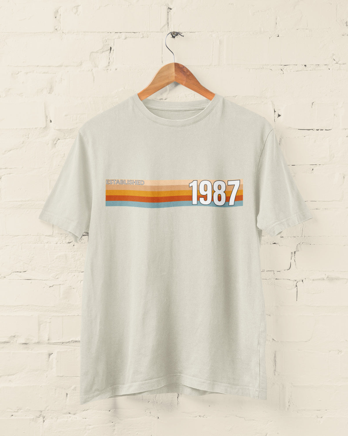 Beige Established 1987 vintage strip T-shirt hanging on a wooden hanger