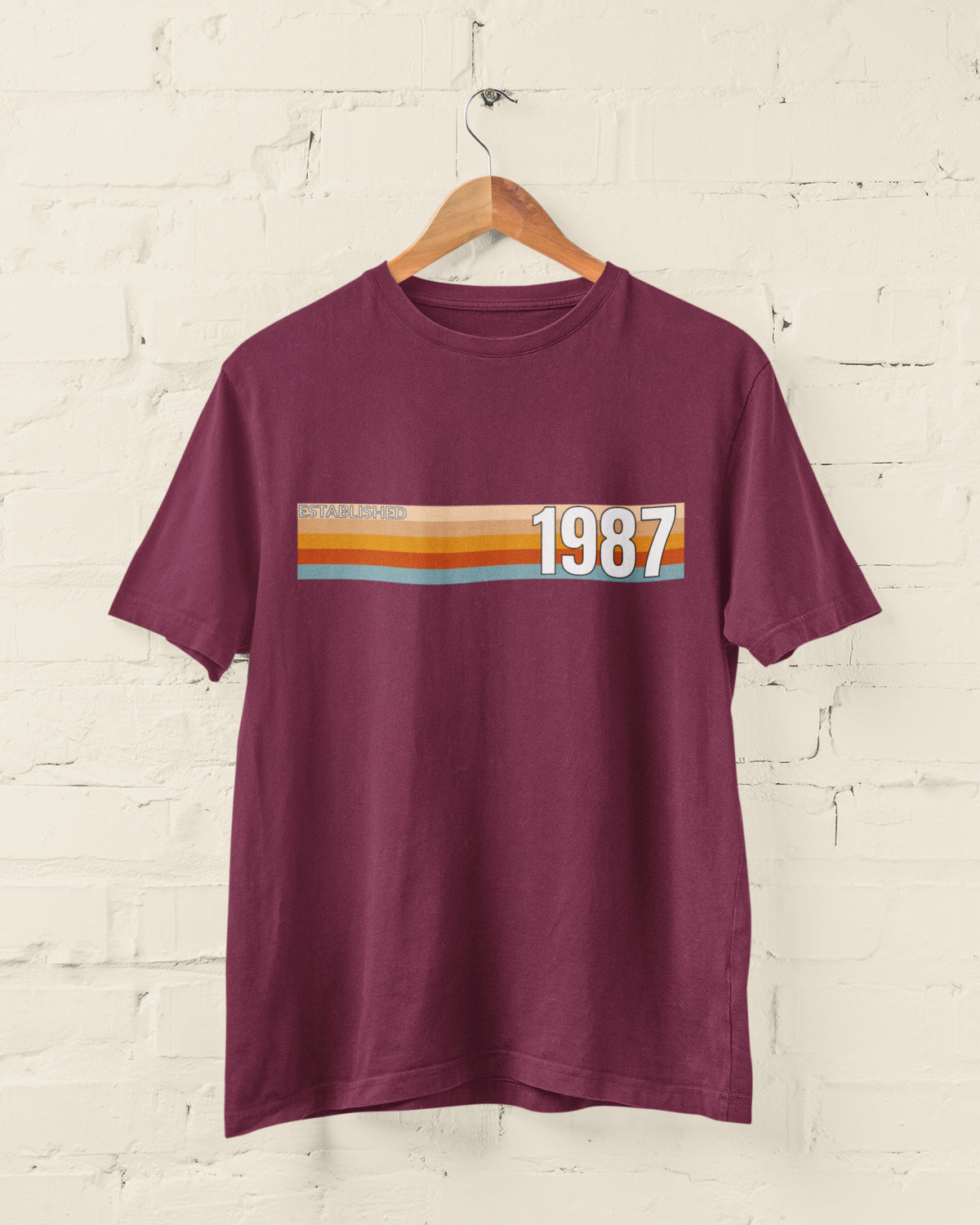 Maroon Established 1987 vintage strip T-shirt hanging on a wooden hanger