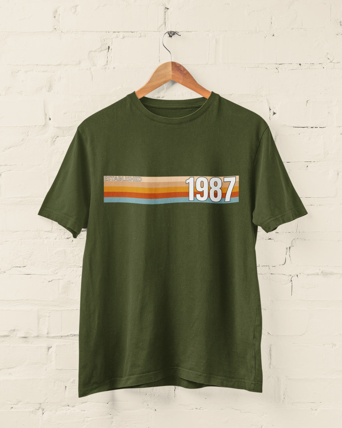 Military Green Established 1987 vintage strip T-shirt hanging on a wooden hanger